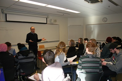 instructor stands in front of students arranged in groups